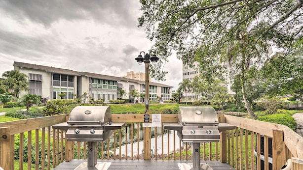 Une terrasse extérieure équipée de deux barbecues, entourée d’une clôture en bois, et offrant une vue sur un bâtiment situé au loin.