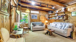 A cozy cabin interior with wooden walls, a sofa, a chair, and a dining table. - Hike to the Coast! Log Cabin on 5 Acres in Bandon (Bandon)