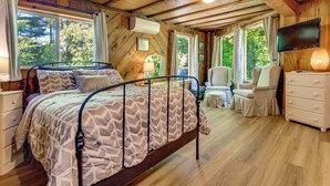 A bedroom with a bed, a television, a dresser, and a window. - Hike to the Coast! Log Cabin on 5 Acres in Bandon (Bandon)