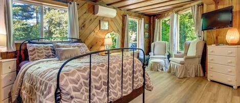 A bedroom with a bed, a television, a dresser, and a window.