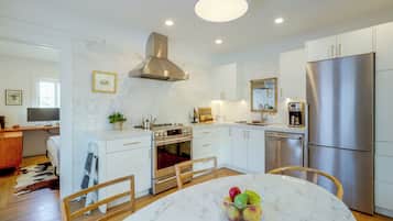 A modern kitchen with white cabinetry, stainless steel appliances, and a marble countertop.