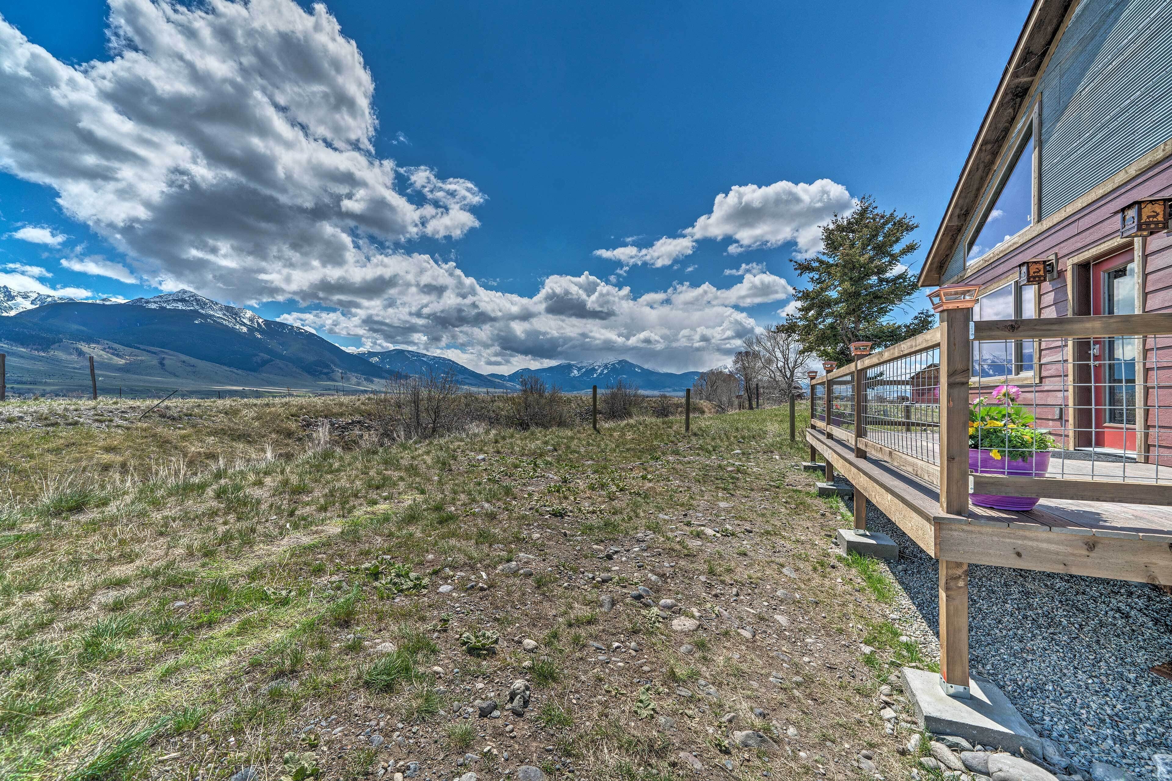 Ein Gebäude mit einer Holzterrasse, Blick auf einen Berg und blauem Himmel.