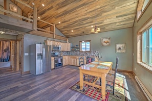 A spacious kitchen with wooden ceiling beams, a dining area with a table and chairs, and a large window providing natural light.