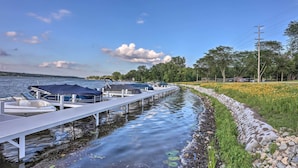 A dock with boats, a stone embankment, and a grassy area with trees.