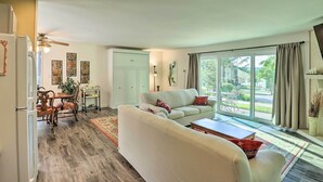 A living room with a sofa, a dining table with chairs, and a kitchen area with a refrigerator.