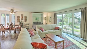 A spacious living room with a large sofa, a coffee table, and a dining area with wooden chairs and a table.