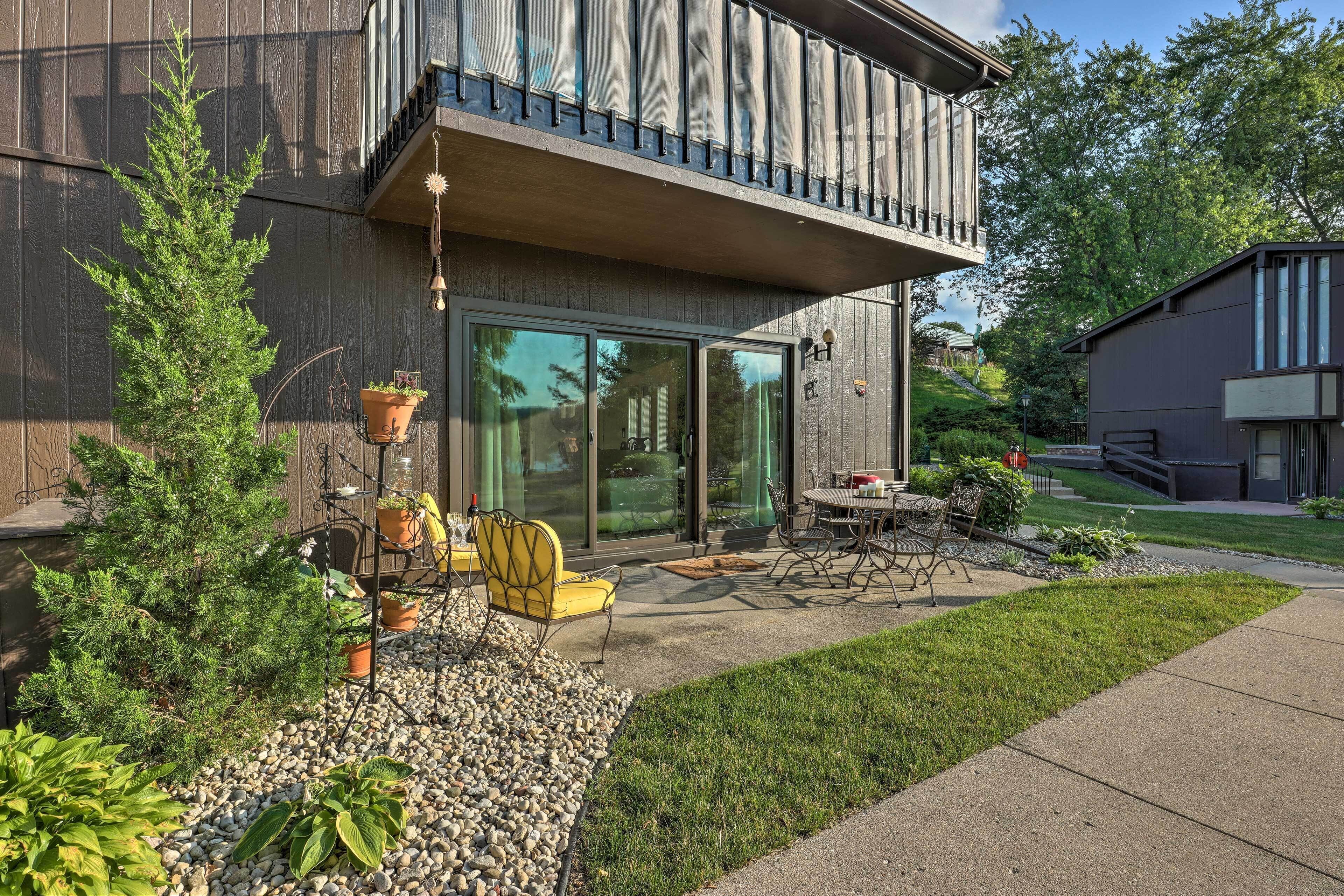 A modern house with a balcony, outdoor seating, and potted plants.