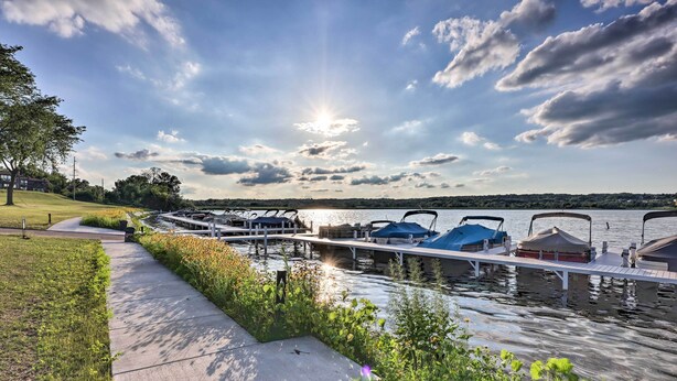 A lakeside dock with boats, a walking path, and a grassy area.