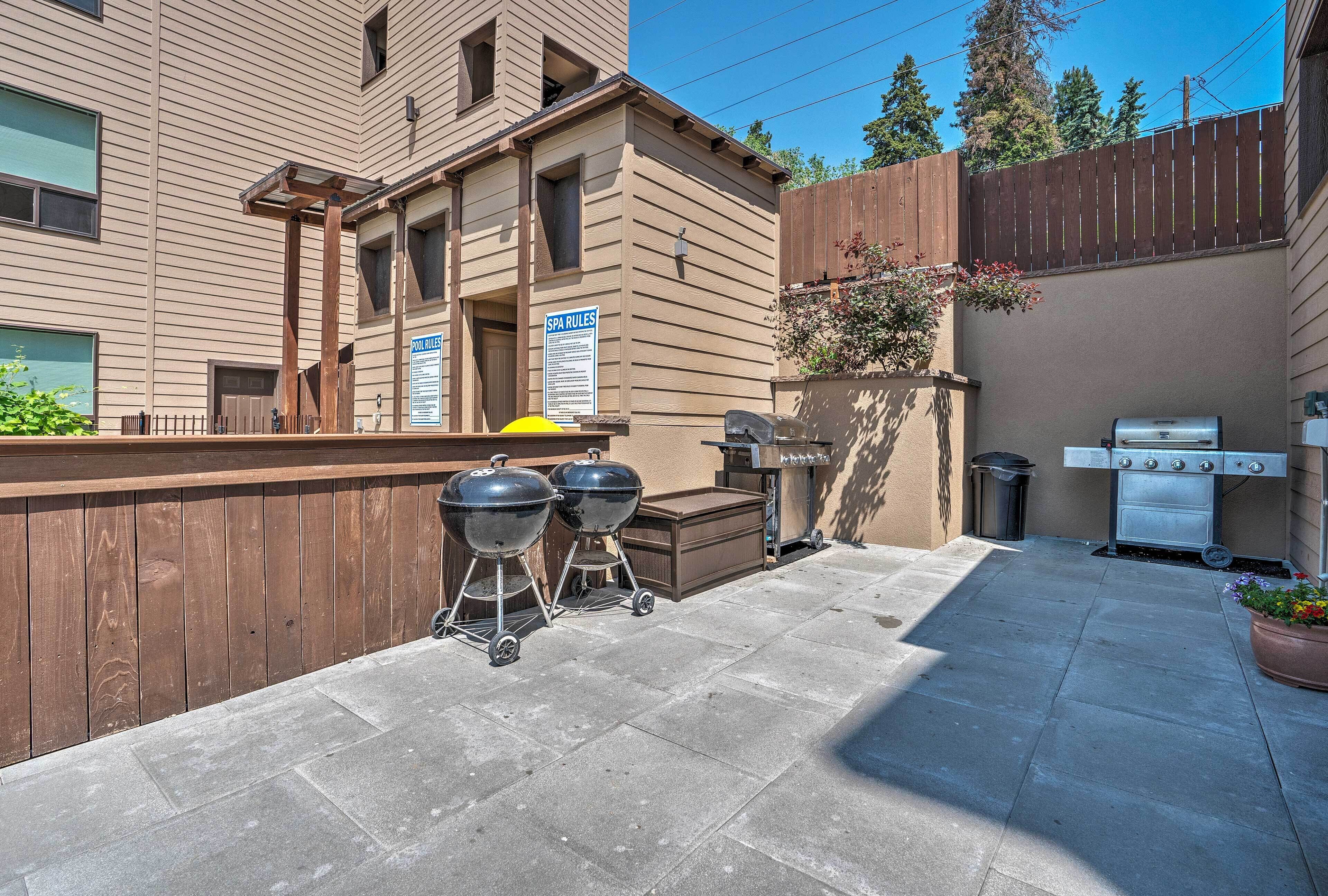 A backyard with a barbecue grill, a trash can, and a wooden fence.