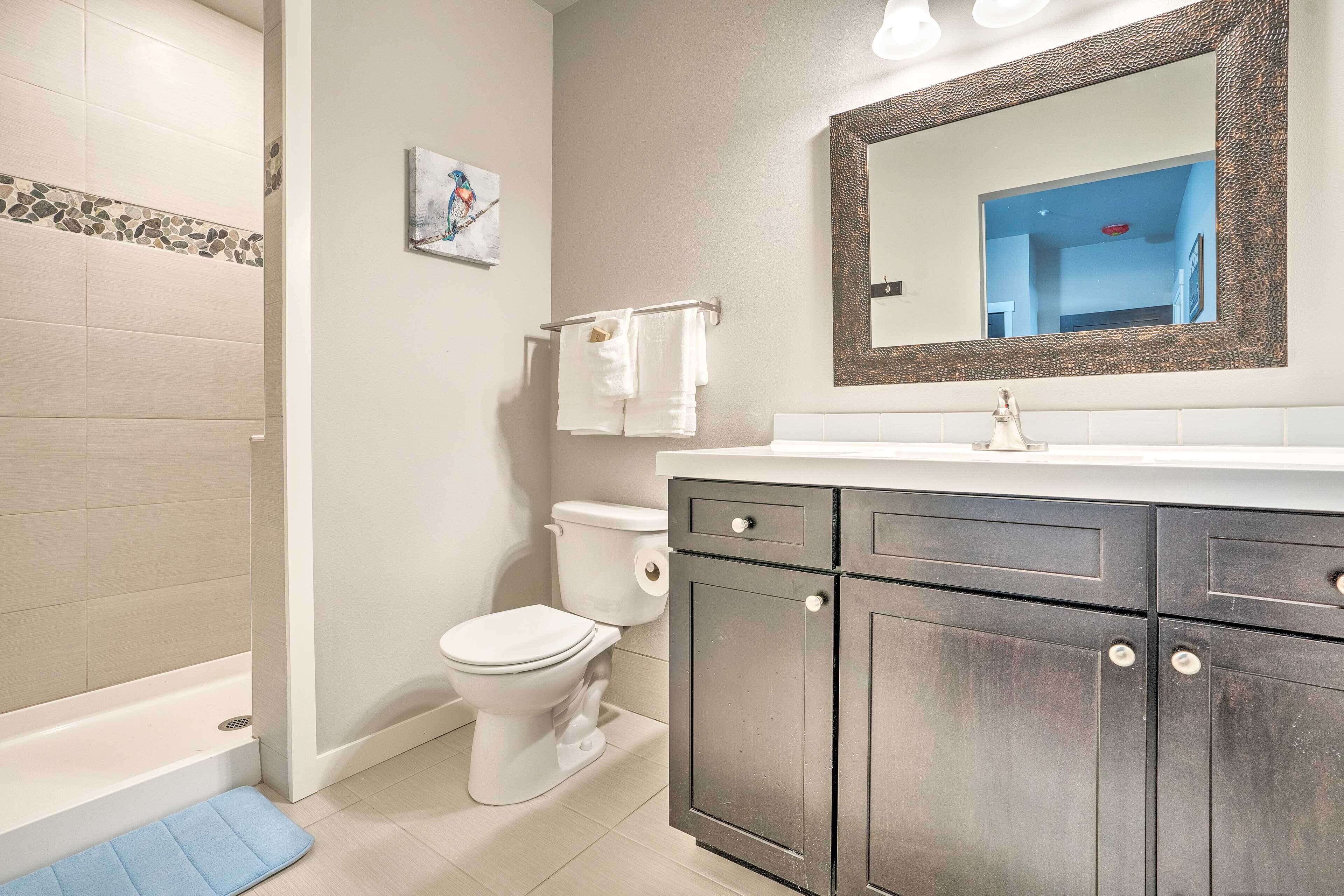 A bathroom with a bathtub, toilet, and vanity with cabinets.