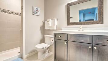 A bathroom with a bathtub, toilet, and vanity with cabinets.