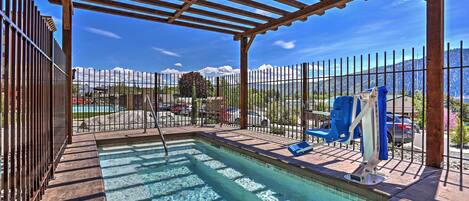 A pool area with a pergola, a fenced pool, and a view of mountains.