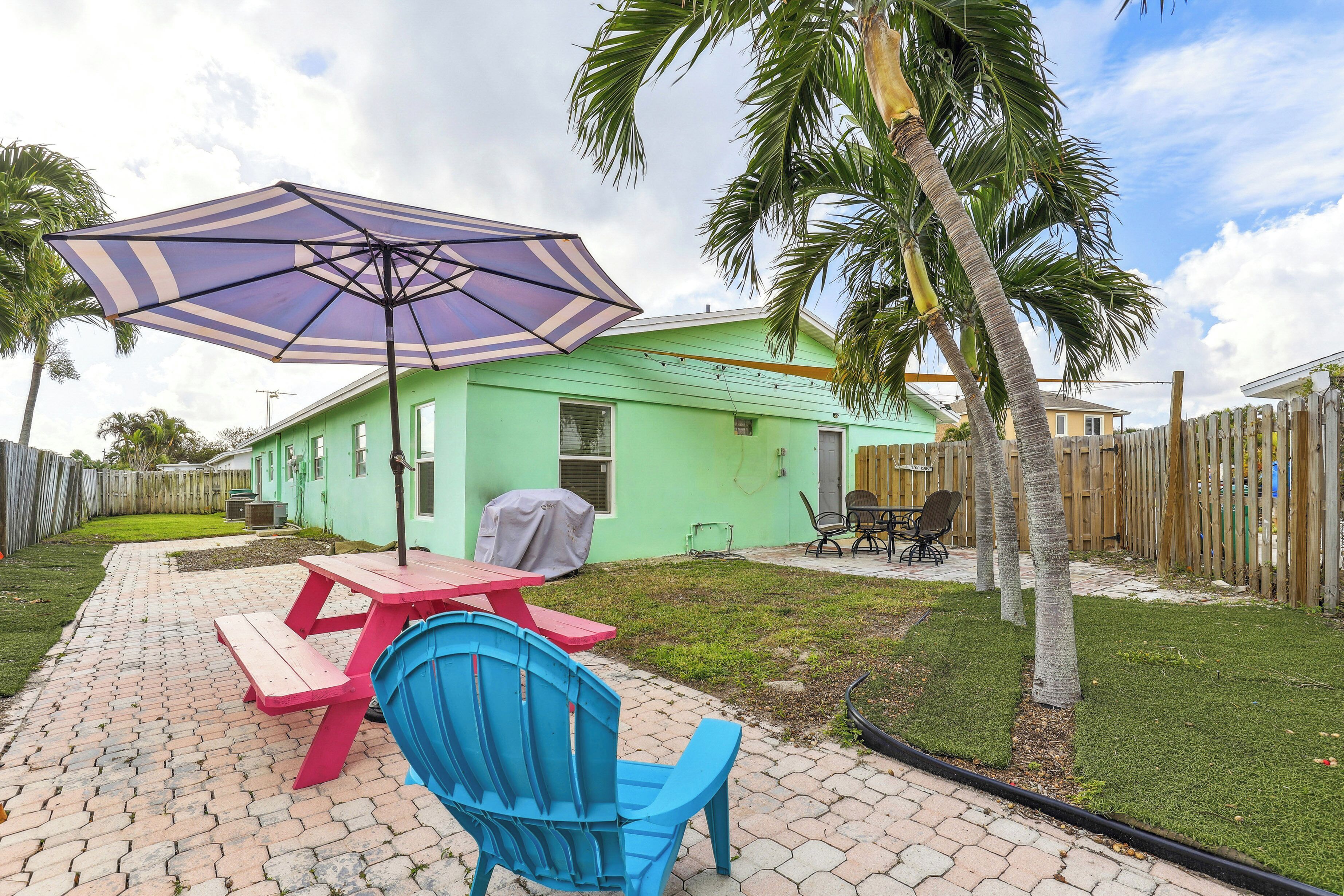 A backyard with a picnic table, chairs, and a large umbrella.