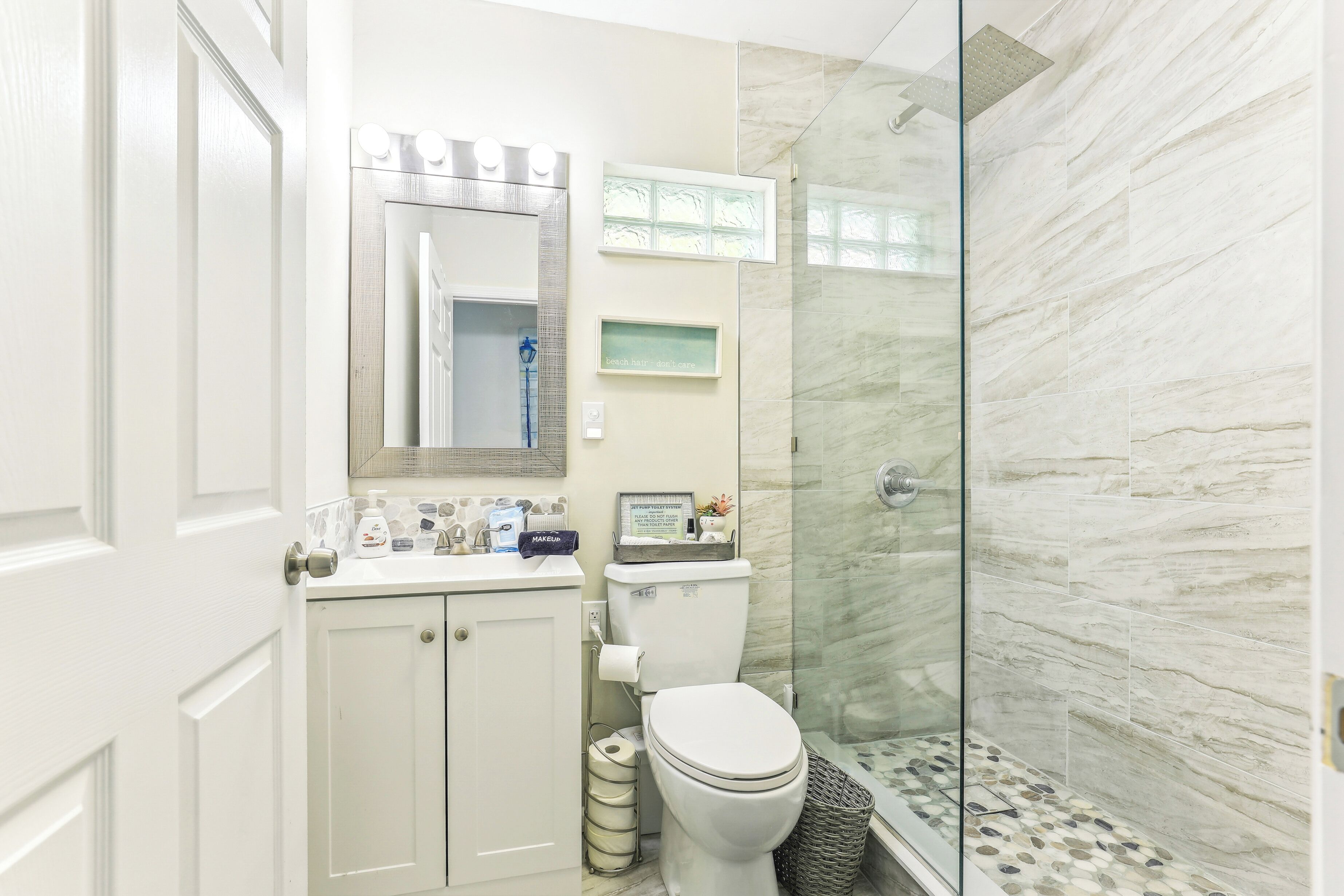 Un baño con inodoro, lavamanos y cabina de ducha de vidrio.