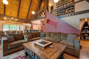 A spacious living area with a large sectional sofa, a wooden coffee table, and a staircase leading to an upper level. - Game Room! Group Lake House, 25 Mi to Yosemite (Groveland)