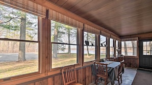 Una cabaña de madera con amplias ventanas que dan a un bosque y una carretera.