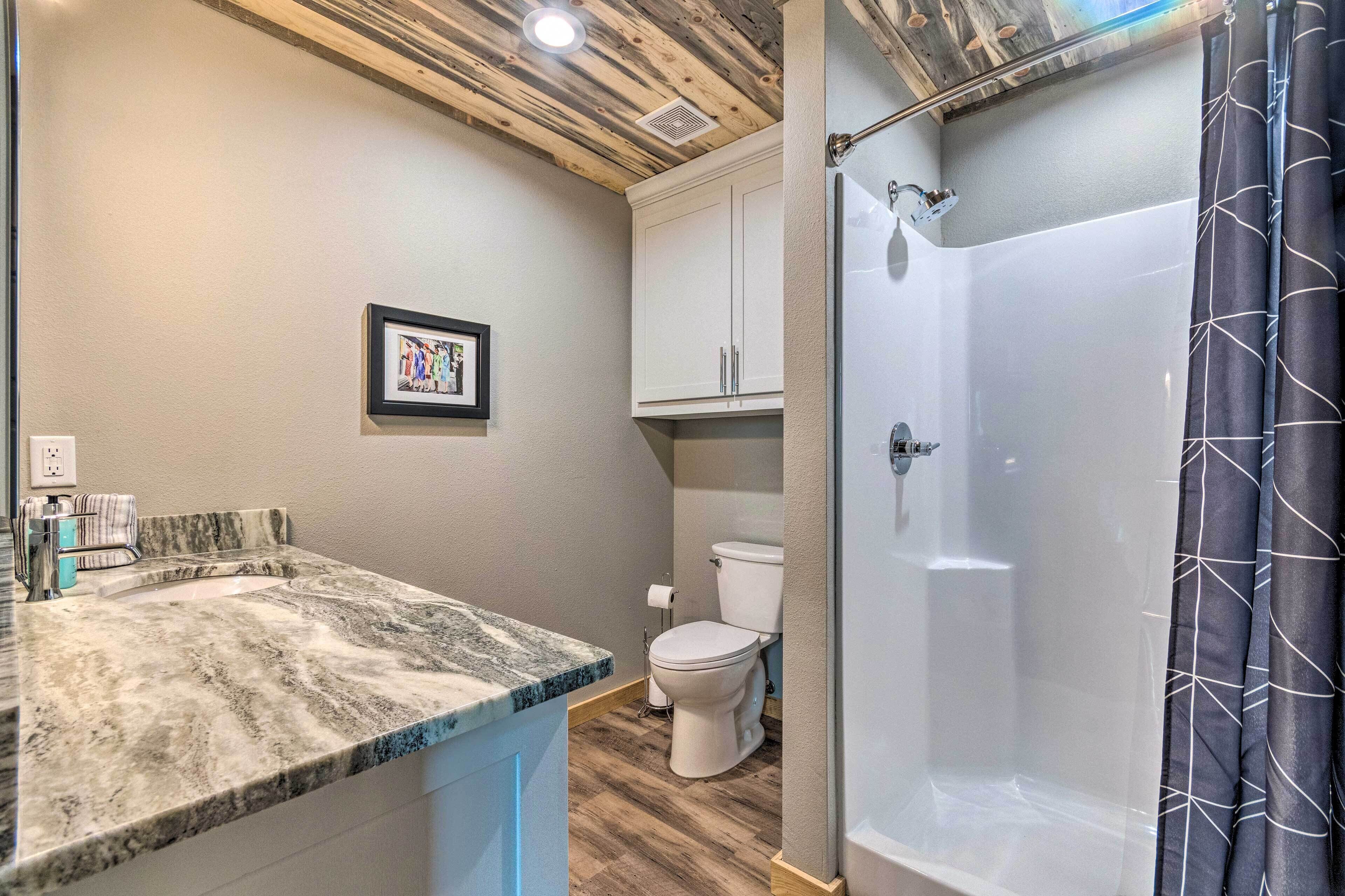 A bathroom with a marble countertop, a toilet, and a glass-enclosed shower.