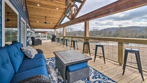 Una terraza techada con un sofá azul, una mesa y taburetes de bar.