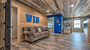 Una habitación con techo de madera, un sofá gris y una pared con las letras 'WIN'.