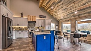 Una cocina moderna con una isla azul, armarios blancos y un salpicadero de piedra.