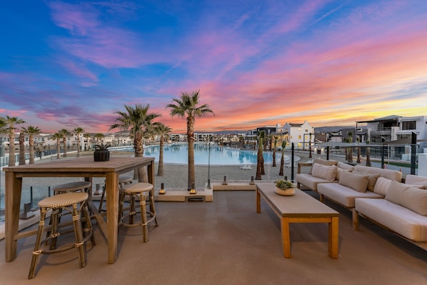A rooftop lounge with a pool, palm trees, and modern furniture.