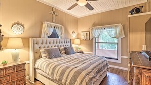 A bedroom with a large bed, wooden dresser, and a ceiling fan. - Country-chic Cotter Home w/ Outdoor Living Space! (Cotter)
