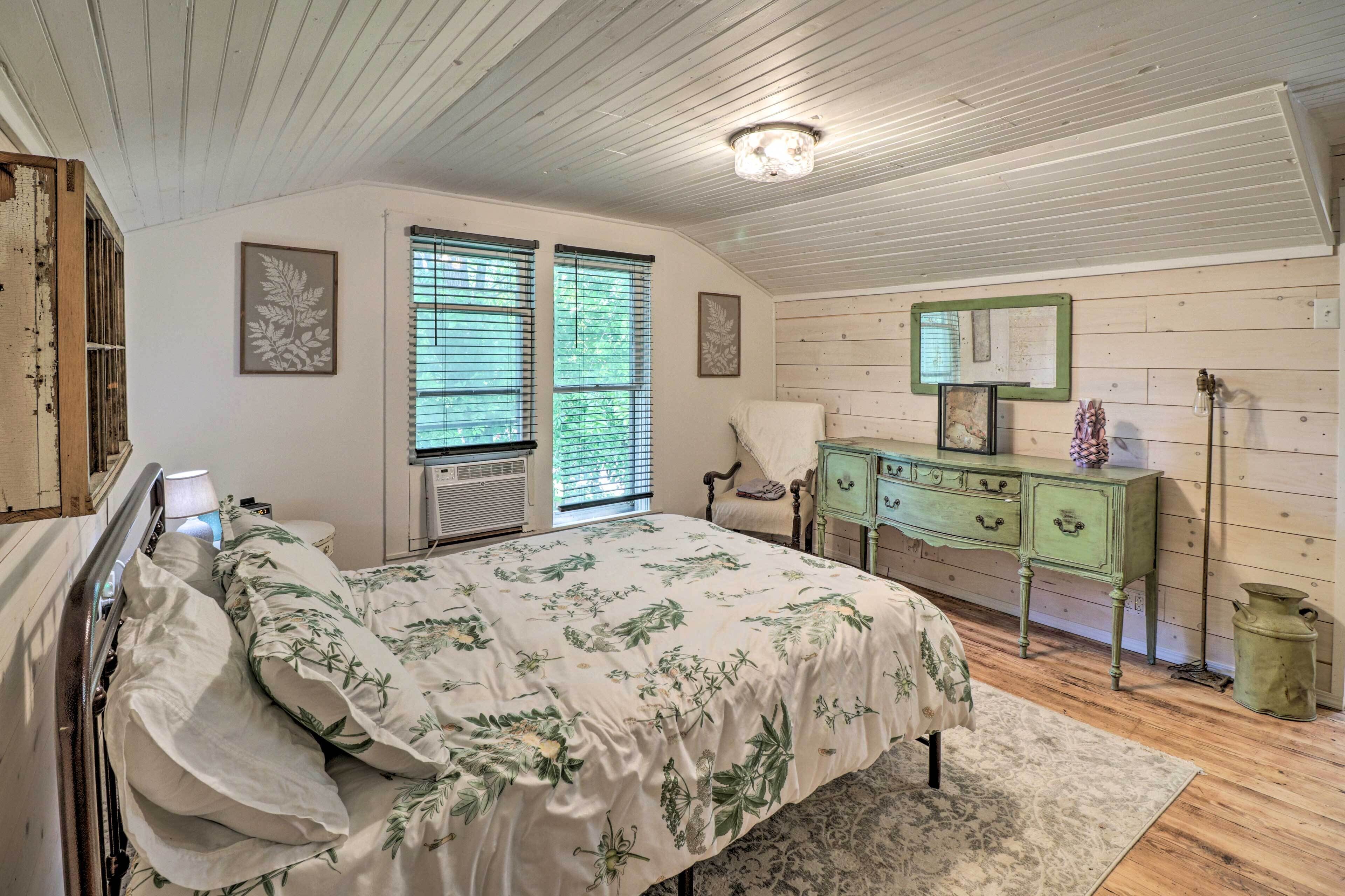 A bedroom with a bed, dresser, and a window with blinds.