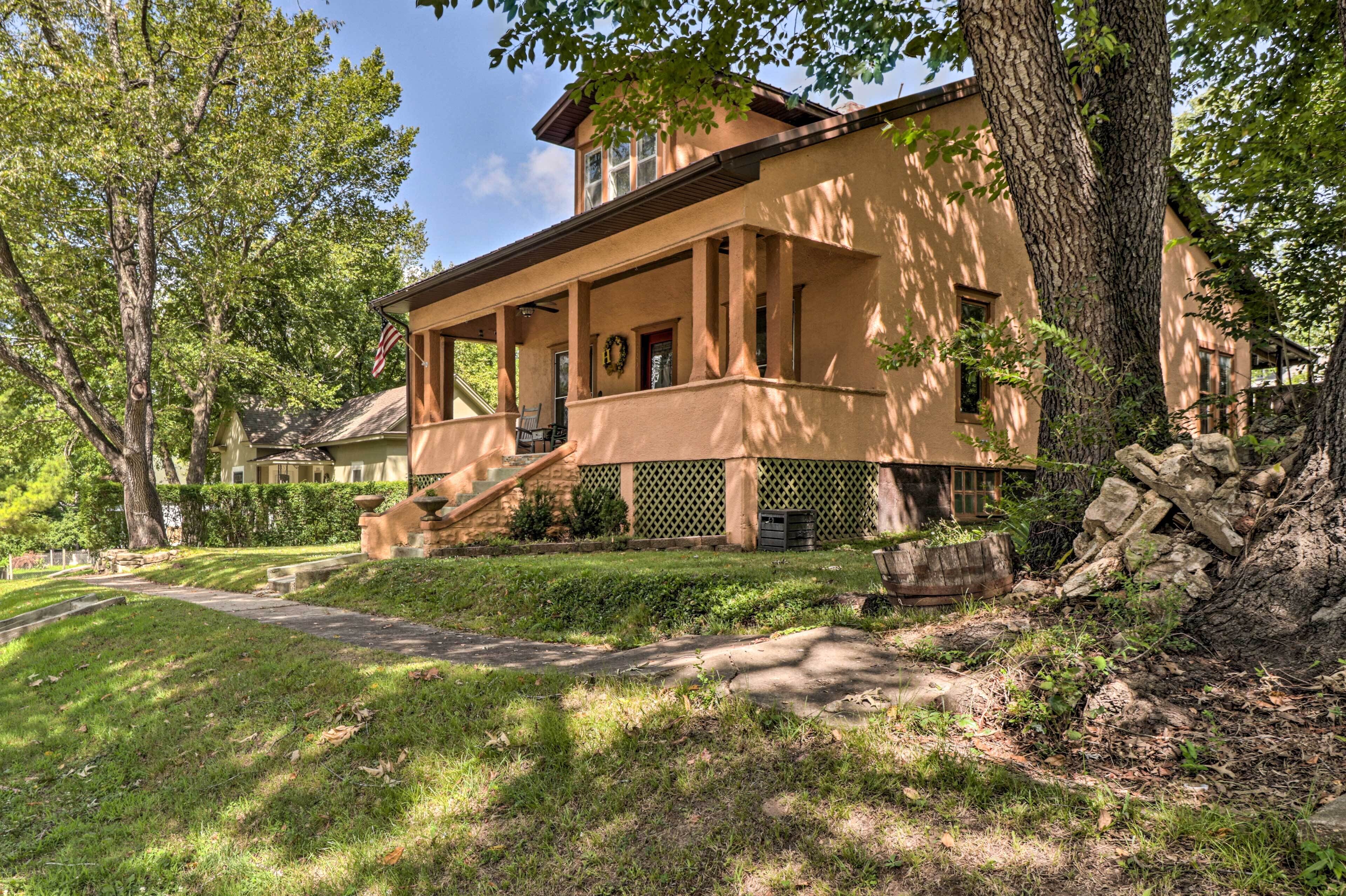 A two-story house with a porch, a front yard, and a large tree.