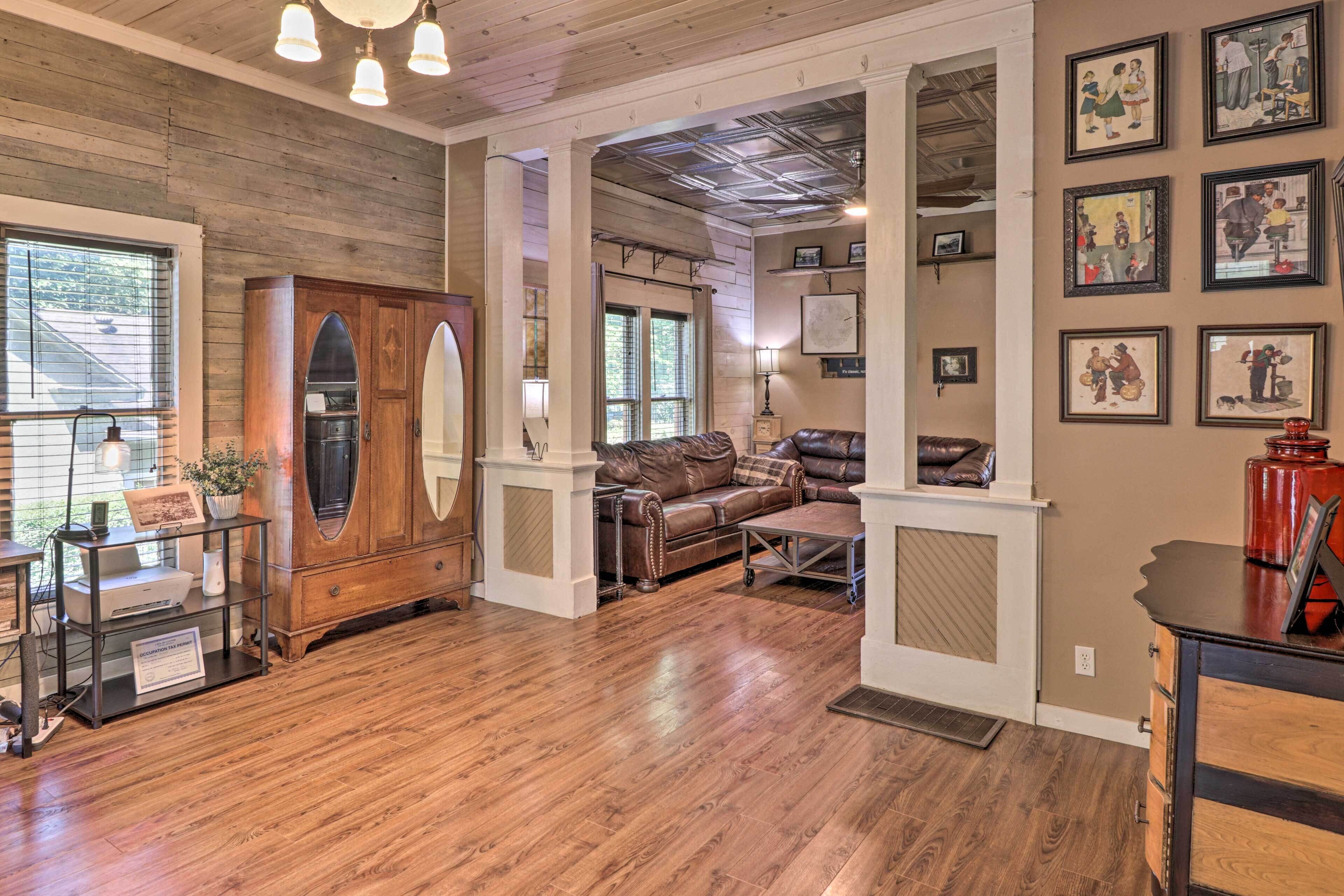 A spacious living area with a wooden floor, leather sofa, and a large cabinet.