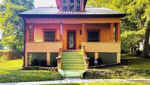 A two-story house with a front porch, a small staircase, and a front yard. - Country-chic Cotter Home w/ Outdoor Living Space! (Cotter)