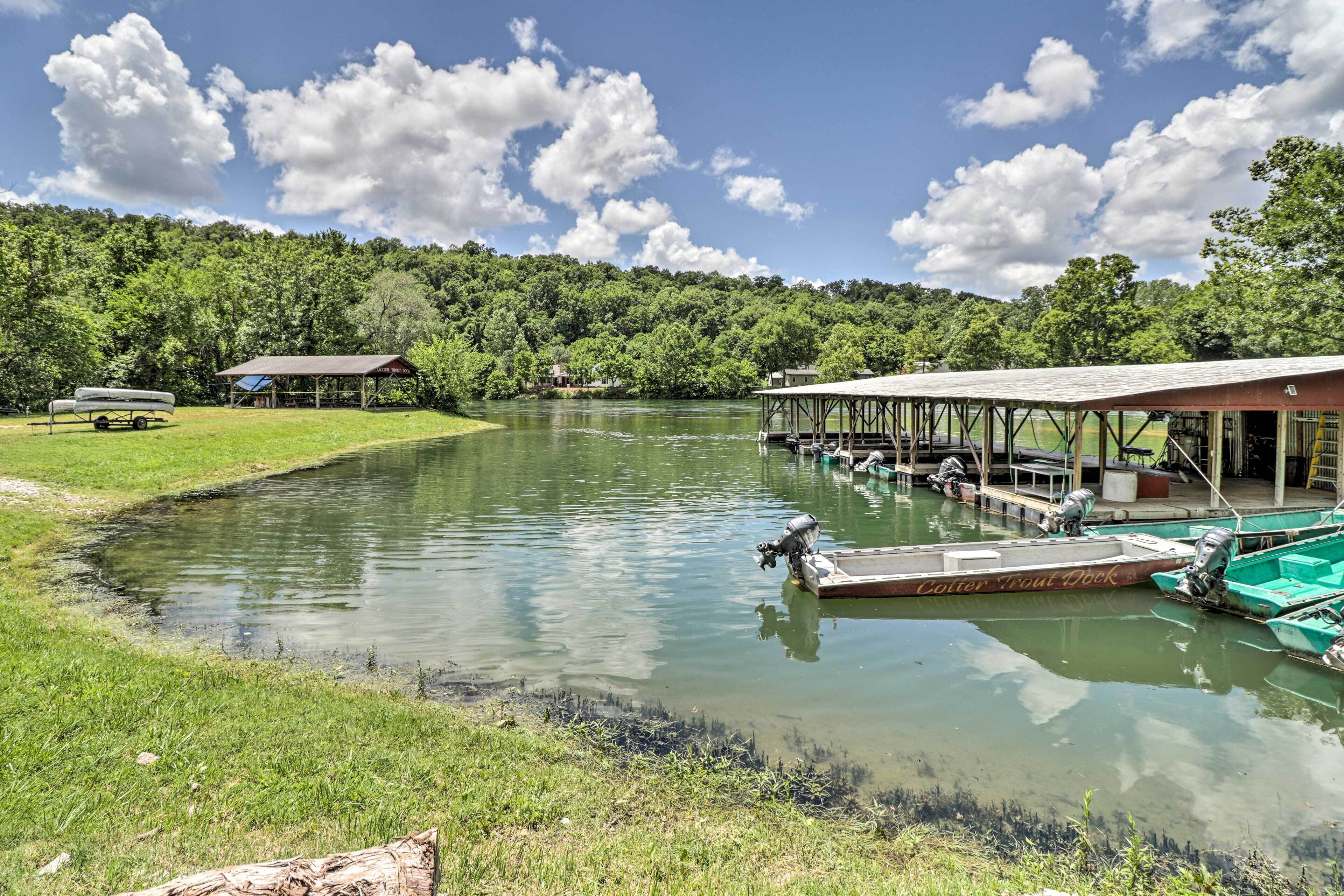 A tranquil lakeside setting with a dock, boats, and a covered pavilion.