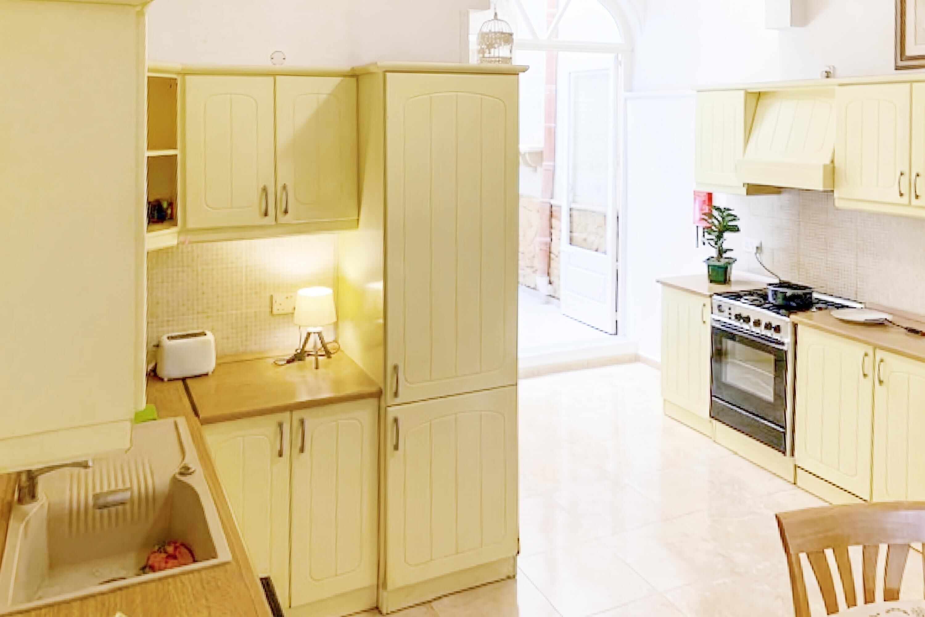 A kitchen with light-colored cabinets, a stove, and a sink.