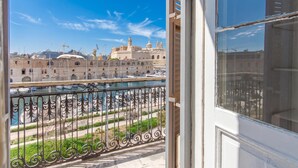 A balcony with a view of a historic building, a body of water, and a construction crane in the distance. - Bougainvillea Breeze & Marina View (Cospicua)