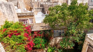A courtyard with stone buildings, a tree, and a small structure with a tiled roof. - Bougainvillea Breeze & Marina View (Cospicua)