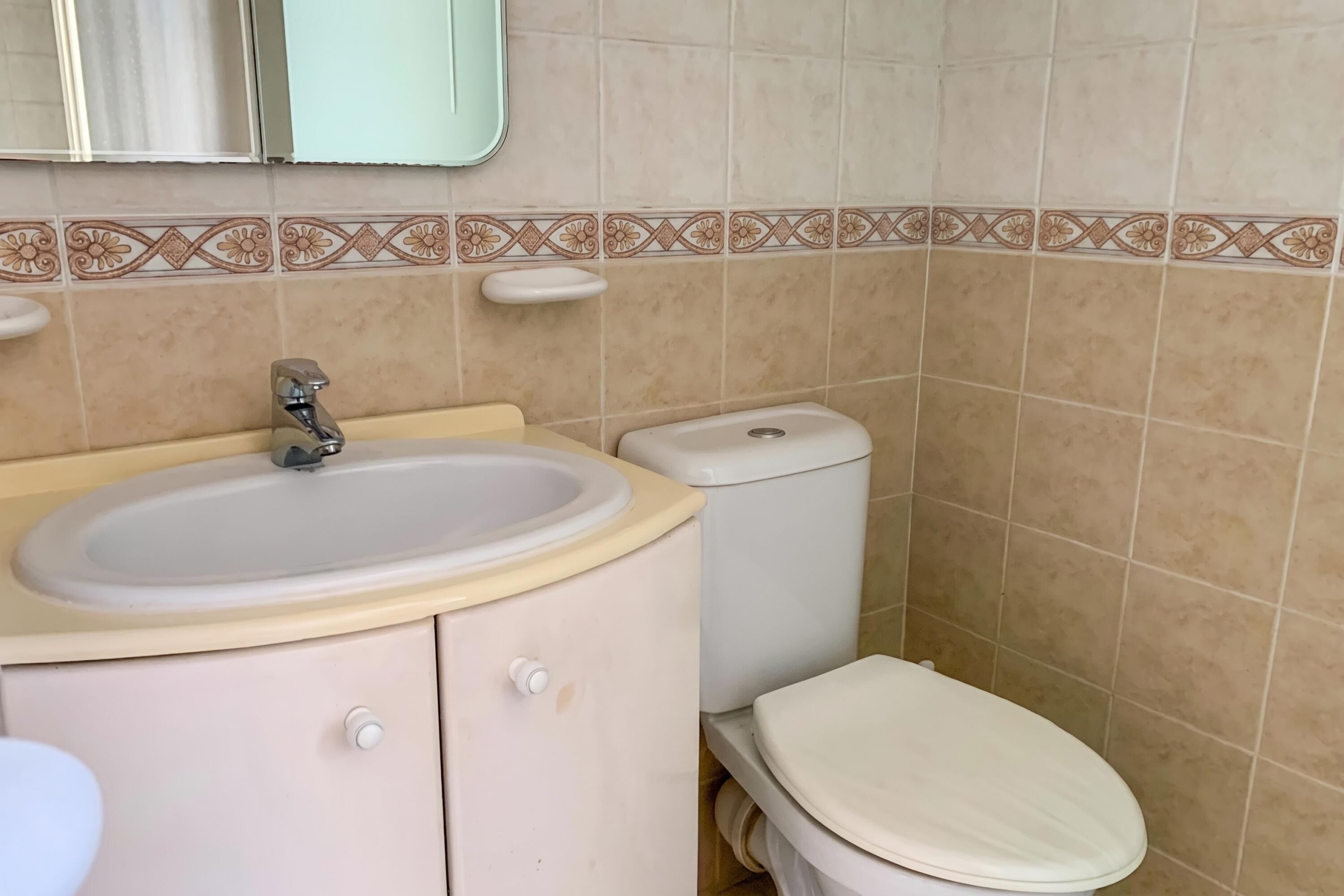A bathroom with a sink, toilet, and mirror.