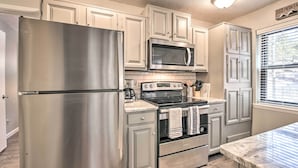 A kitchen with stainless steel appliances, white cabinetry, and a window with blinds. - Angel Fire Condo w/ Fireplace < 1 Mi to Ski Resort (Angel Fire)