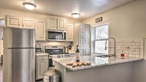 A modern kitchen with white cabinetry, stainless steel appliances, and a marble island. - Angel Fire Condo w/ Fireplace < 1 Mi to Ski Resort (Angel Fire)