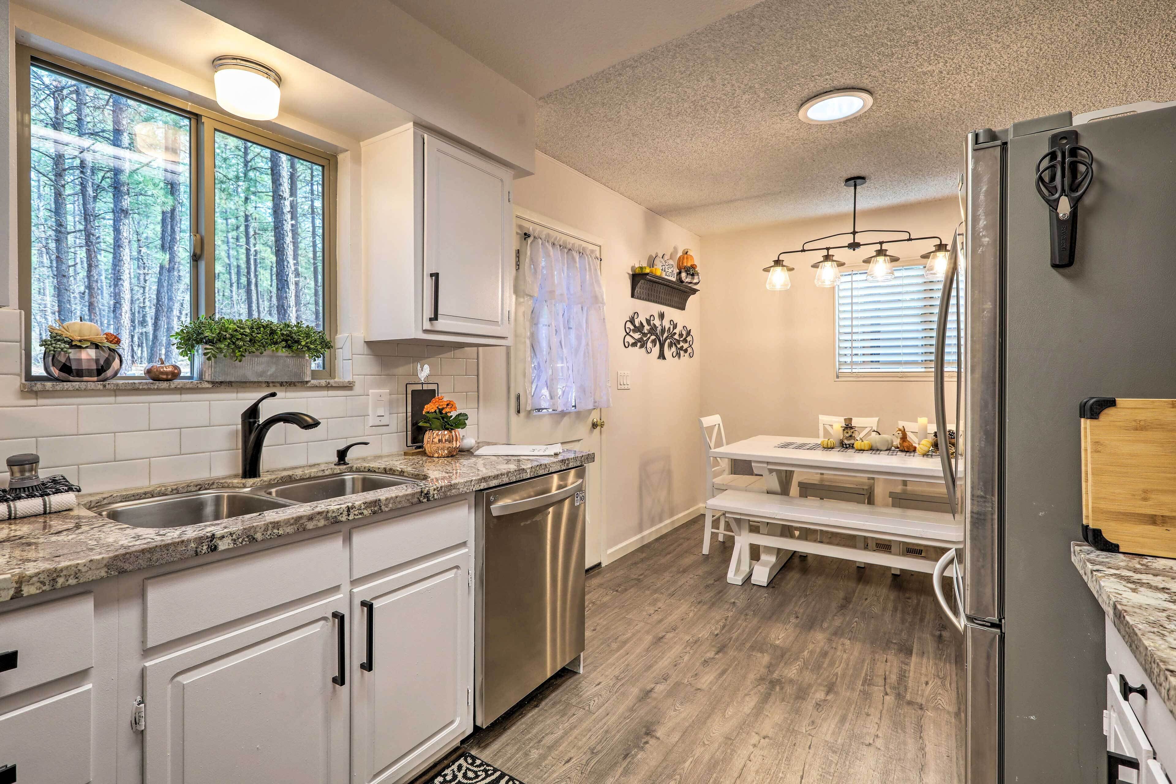 A modern kitchen with white cabinets, a stainless steel dishwasher, and a dining area with a bench and table.