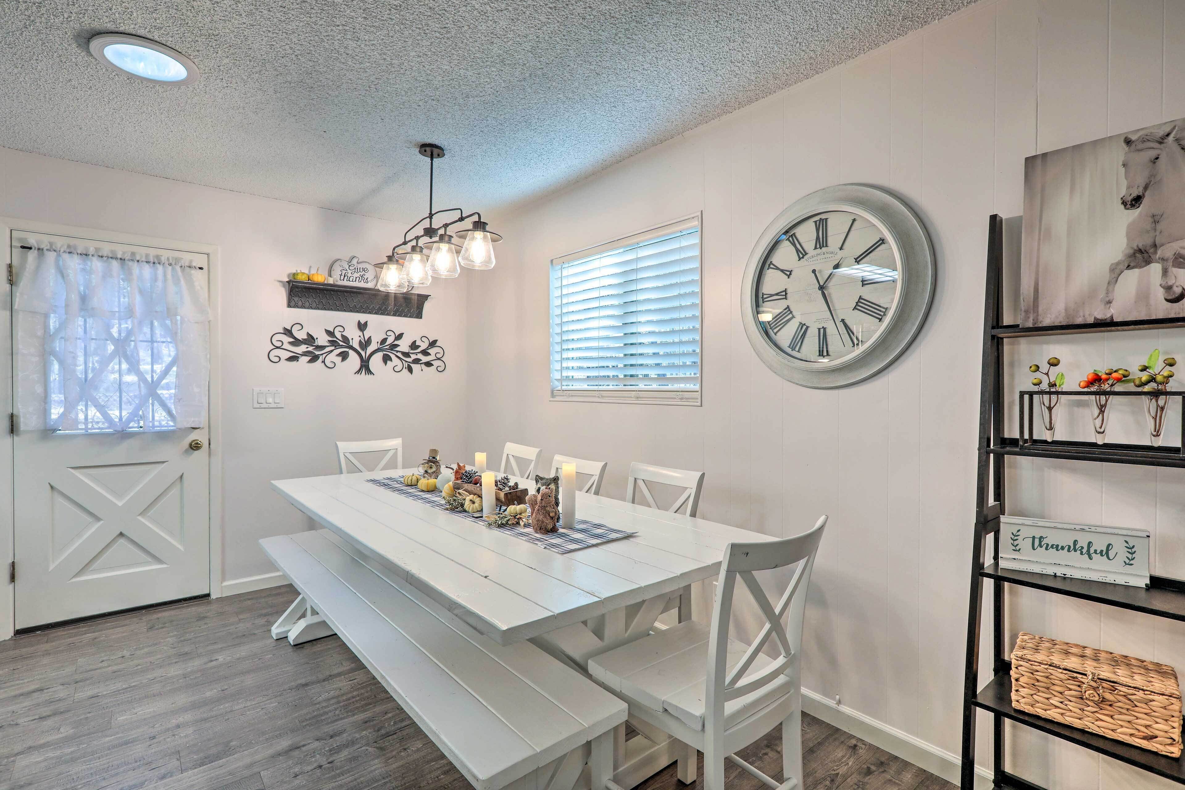 A dining area with a white table, benches, and a clock on the wall.