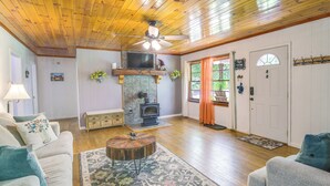 A cozy living room with a fireplace, wooden floors, and a ceiling fan. - Great Smoky Mountains Retreat w/ Fire Pit & Views! (Sevierville)