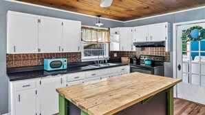 A kitchen with white cabinets, a wooden countertop, a microwave, a sink, and a stove. - Great Smoky Mountains Retreat w/ Fire Pit & Views! (Sevierville)