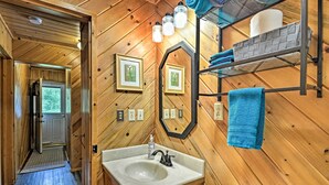 A wooden bathroom with a sink, mirror, and towel rack. - Near Snowmobiling! Riverfront Traverse City Cabin (Traverse City)