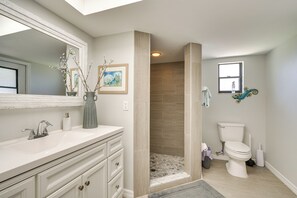 Une salle de bain avec un meuble-lavabo blanc, une douche aux carreaux beiges et des toilettes.