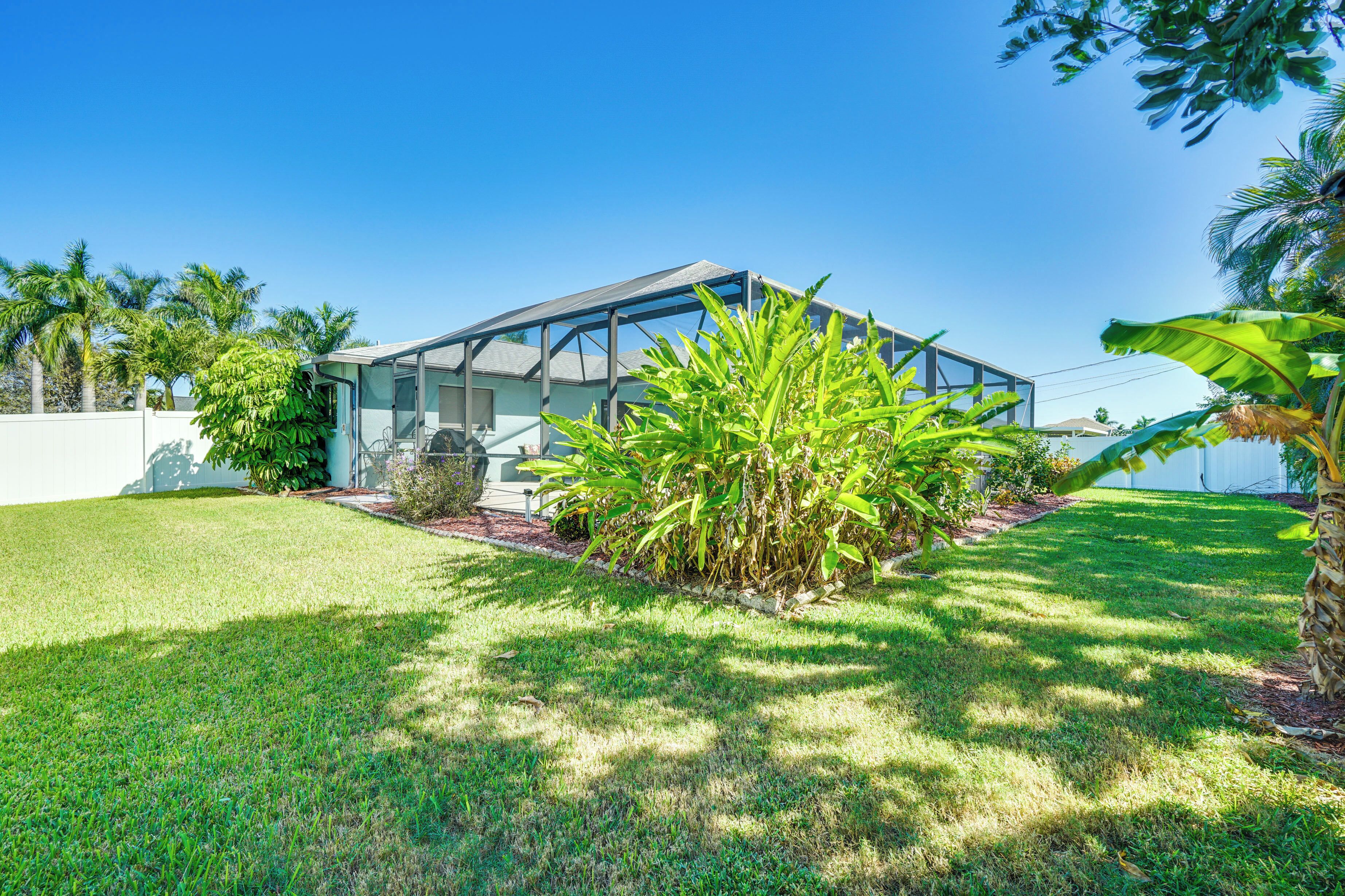 A modern house with a glass conservatory, surrounded by a well-maintained lawn and tropical plants.