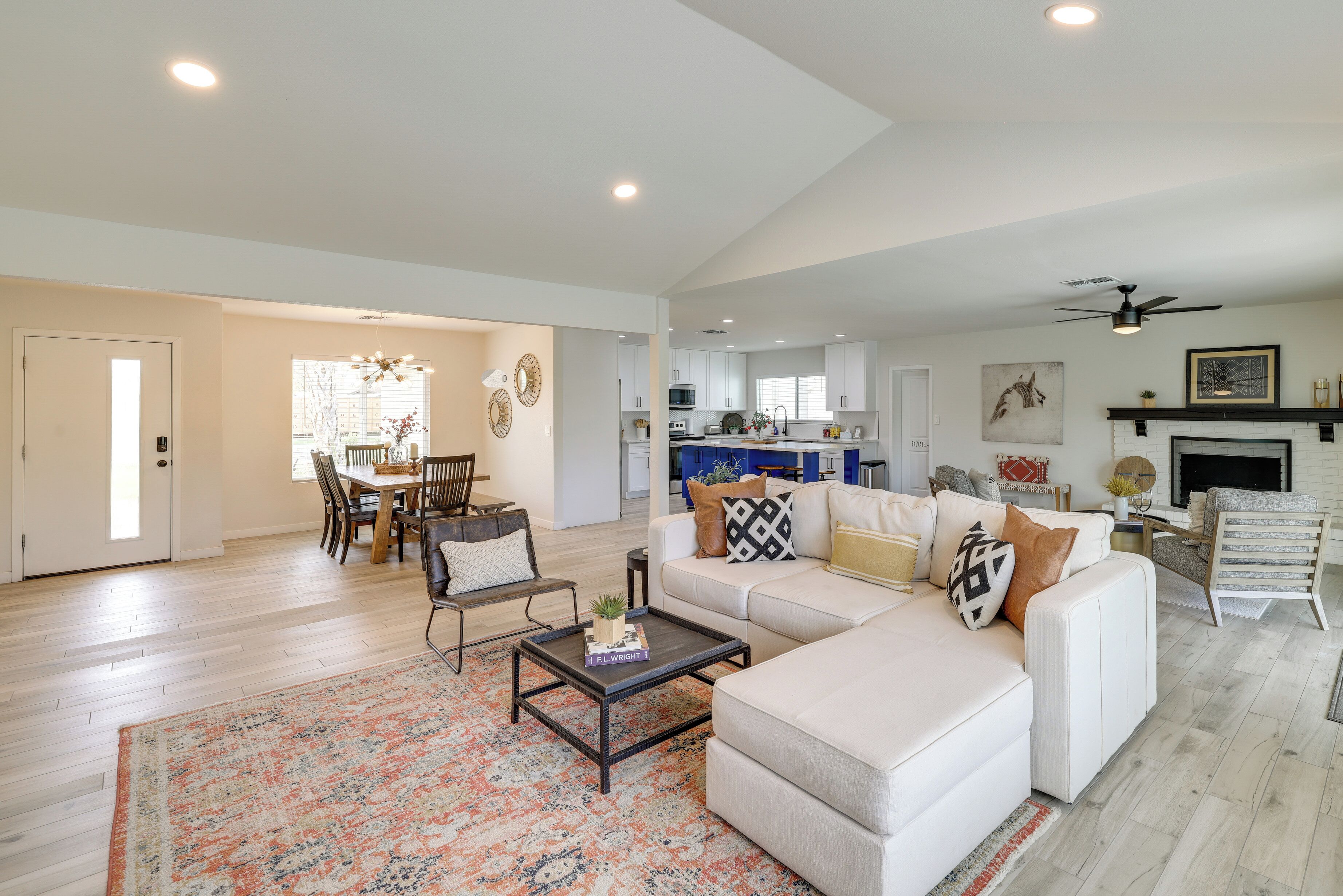 A spacious living room with a white sofa, a coffee table, and a dining area with a wooden table and chairs.