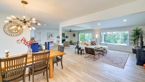 A spacious living area with a wooden dining table, chairs, and a modern chandelier. There is a sofa set and a coffee table in the background. - 6 Mi to Lookout Mountain: Scottsdale Home w/ Grill (Scottsdale)