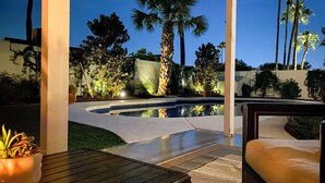 A pool area with a curved edge, surrounded by palm trees and potted plants, with a bench and a table in the foreground. - 6 Mi to Lookout Mountain: Scottsdale Home w/ Grill (Scottsdale)
