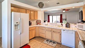 A modern kitchen with wooden cabinets, a white refrigerator, a dishwasher, and a microwave.
