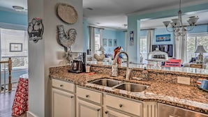A kitchen with granite countertops, stainless steel appliances, and a large window. - Family Beach Home; Walk to N Litchfield Beach (Pawleys Island)