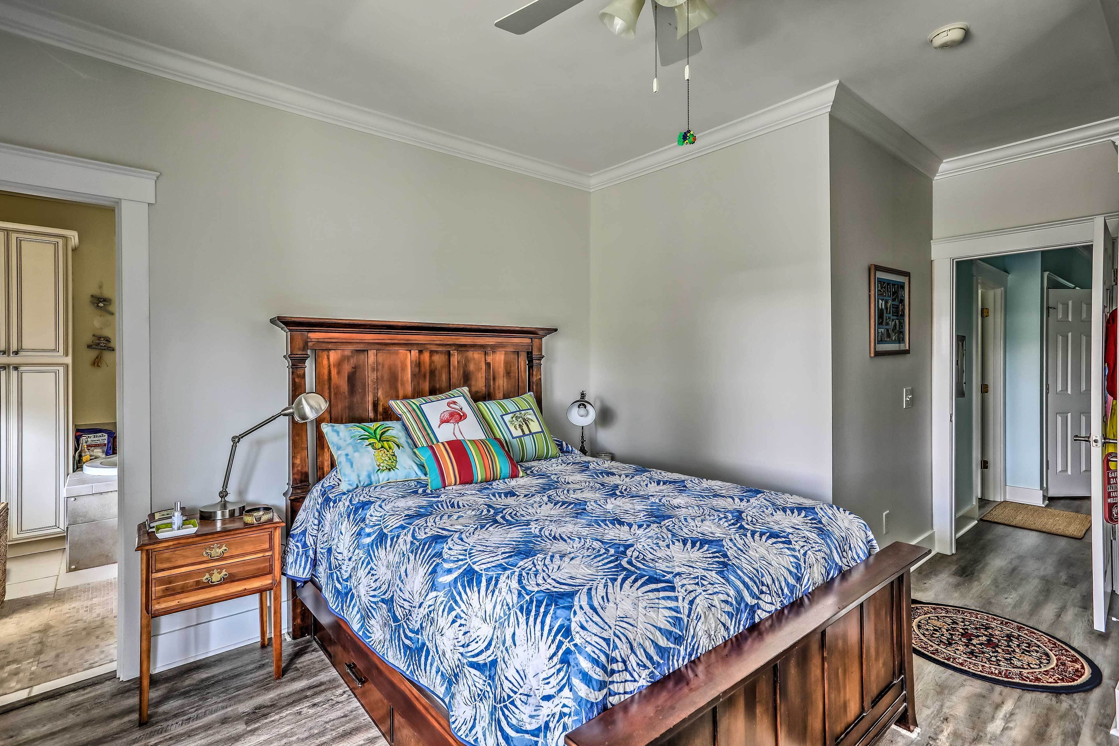 Une chambre à coucher avec un lit en bois, une table de chevet, une lampe de bureau et une étagère fixée au mur.
